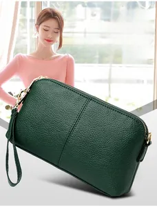 Close-up of dark green lychee grain leather handbag with gold metal zippers
