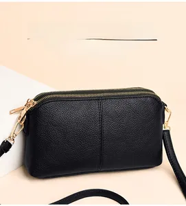 Detailed macro view of black pebbled leather texture and dual gold-tone zipper compartments