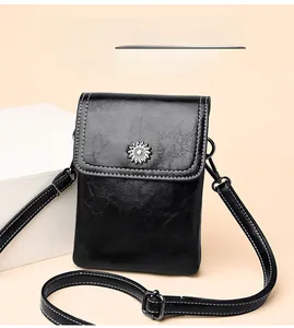 Detail of black crossbody bag featuring contrast stitching and floral metal buckle accent
