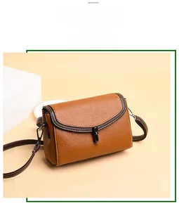 Close-up of brown pebbled leather texture, white stitching and metal buckle on crossbody bag