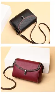 Detail of pebbled leather shoulder bags in black and burgundy with contrast stitching