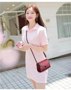 Detail of burgundy pebbled leather crossbody bag shown on model with outdoor background