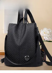 Detail of black woven embossed leather backpack with silver metal shield logo plaque