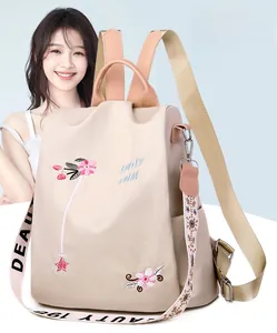 Detail of pink floral embroidery and stylish letter straps on a beige nylon backpack