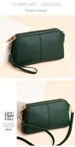 Detailed view of dark green litchi texture leather clutch with golden zippers and straps