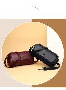 Détail de sacs cylindriques en cuir souple bordeaux et noir avec fermeture magnétique