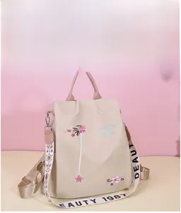 Detail of floral embroidery and printed strap on beige Oxford fabric backpack