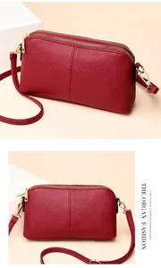 Detail view of red lychee grain leather crossbody bag with three-tier gold zipper design