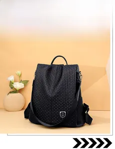 Detail of black woven texture backpack featuring metallic shield logo and sturdy top handle