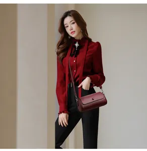 Détail du sac cylindrique bordeaux en cuir grainé avec bandoulière et métal poli