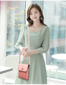 Pink small crossbody phone bag with daisy metal buckle worn by a model in bright setting