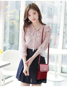 Detail of dark red glossy leather mini crossbody bag with petal-shaped metal clasp