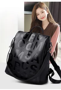 Detail of black pebbled leather backpack with embossed letters and top handle