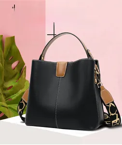 Close-up of black lychee grain bucket bag featuring brown leather handle and wide floral strap