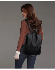 Detail of black backpack showing embossed texture and dark metal logo on synthetic leather