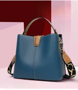 Detail of blue litchi grain bucket bag with brown handles and patterned fabric strap
