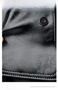 Close-up of black leather bag featuring sunflower metal ornament and magnetic snap