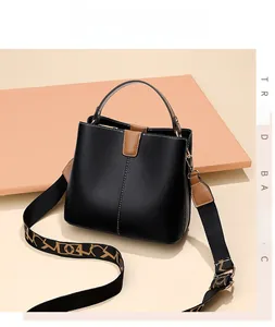 Detail of black pebbled leather bucket bag with brown handles and patterned strap