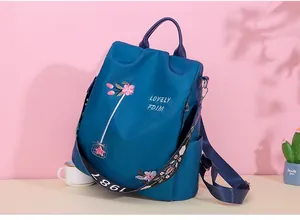 Detail view of floral embroidery and colorful jacquard strap on a blue oxford backpack