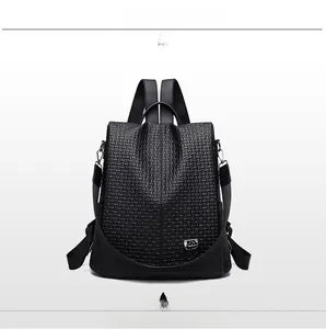 Close-up of the woven texture and metal shield logo on a black anti-theft backpack