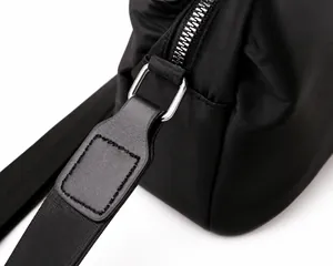 Dettaglio macro della cerniera in metallo argento e cinturino in nylon su una borsa nera
