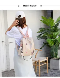 Detail of floral embroidery and branded strap on a beige nylon backpack for women