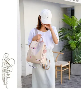 Detail of floral embroidery on beige Oxford fabric backpack with woven shoulder straps