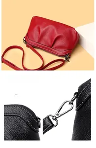 Macro detail of lychee grain leather with contrast stitching and metal hook on crossbody bag