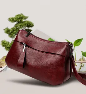 Dettaglio della borsa bordeaux in ecopelle con tasche multiple a zip e texture ruvida