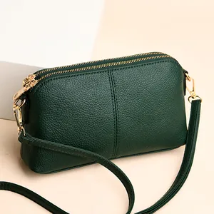 Dark green lychee leather crossbody bag with double gold zippers and compact design