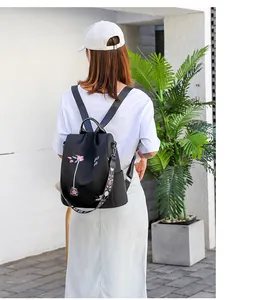 Close-up of black Oxford backpack with floral embroidery and colorful woven strap