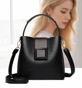 Detail of black litchi grain leather bucket bag with metallic buckle and shoulder strap