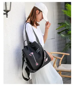 Detail of floral embroidery and branded strap on a black waterproof Oxford backpack