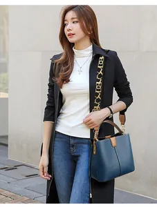Blue leather bucket bag with brown handles and patterned strap shown on a street model