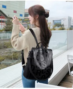 Detail of black pebbled leather backpack featuring embossed lettering and side pocket