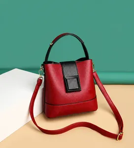 Detail of red and black bucket bag featuring pebbled leather and a metal square buckle
