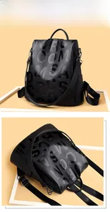 Macro shot of black pebbled leather backpack showing bold 3D embossed lettering details