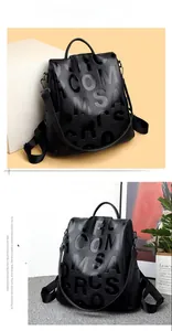 Detail showing litchi grain leather texture and 3D embossed letters on black backpack