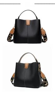 Detailed view of black lychee leather bucket bag with brown trim and wide strap