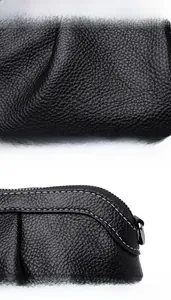 Close-up of black litchi grain leather bag with white stitching and zipper closure detail