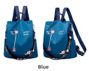 Detailed view of blue waterproof nylon backpack with floral embroidery and wide strap