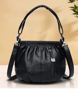 Detail of black faux leather handbag showing pleated texture and drop-shaped metal zipper pull