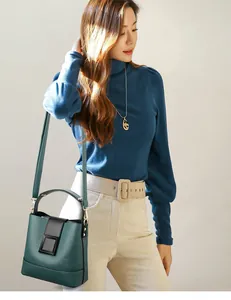 Detail of dark green lychee leather bucket bag with black strap and square metal buckle