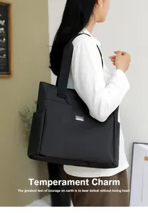Detailed side view of black nylon tote bag with silver plate and wide shoulder strap