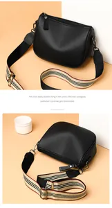 Detail of black lychee grain saddle bag with a colorful striped canvas shoulder strap
