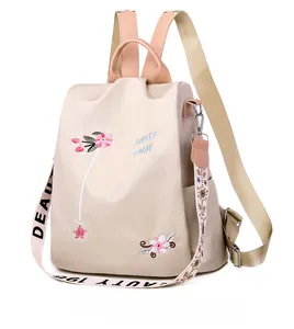 Side view of beige oxford backpack with pink floral embroidery and star pendant