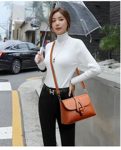 Détail d'un sac à bandoulière orange en cuir grainé avec fermeture à rabat chic