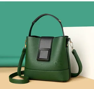 Detail of green bucket bag with lychee leather texture and golden metal hooks