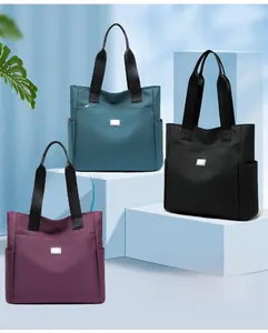 Detailed view of lightweight nylon tote bags in green, black, and purple with side pockets