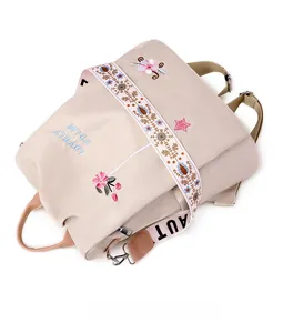Detail of beige nylon backpack featuring floral embroidery and ethnic patterned straps